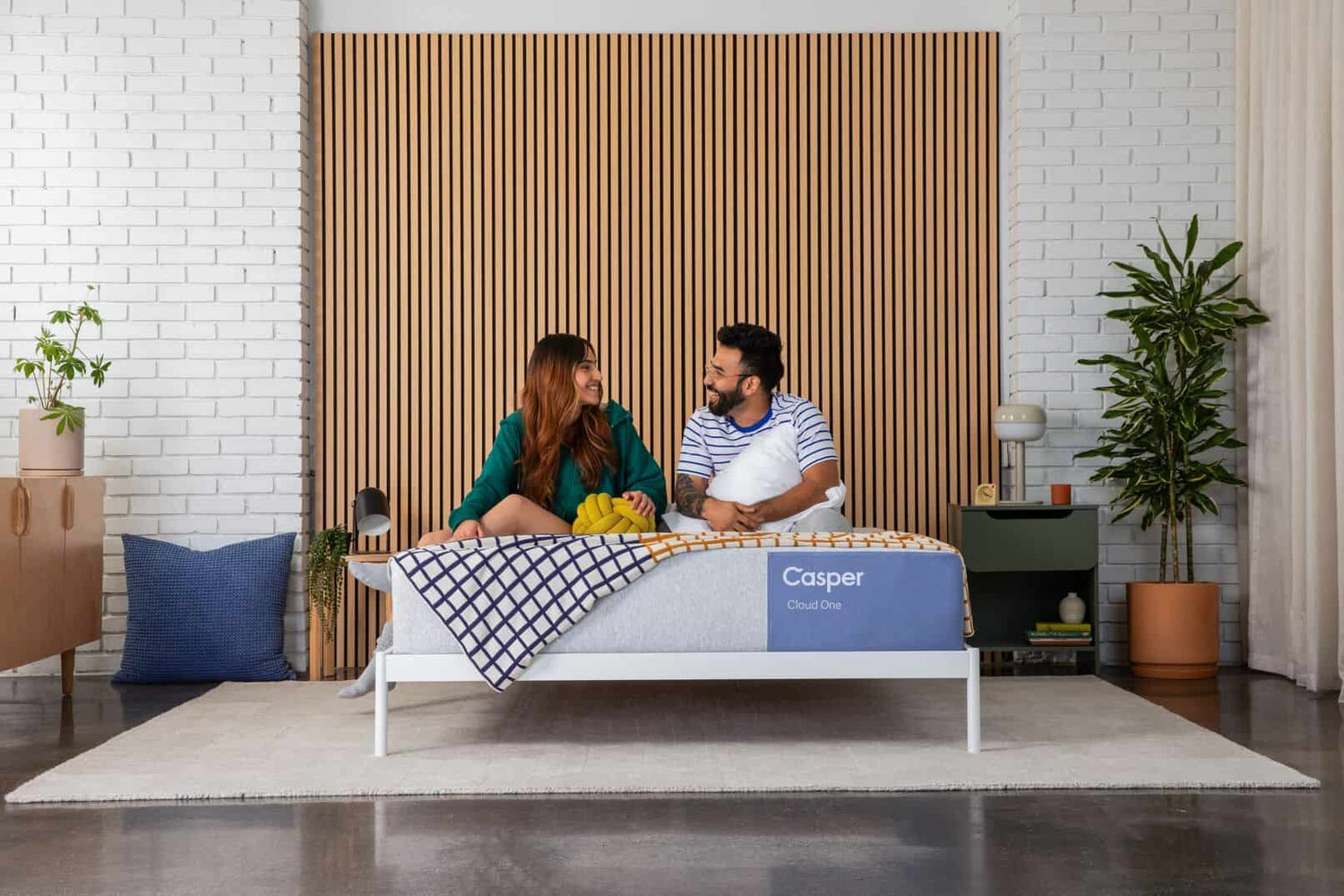 Happy couple sitting on Casper Cloud One mattress