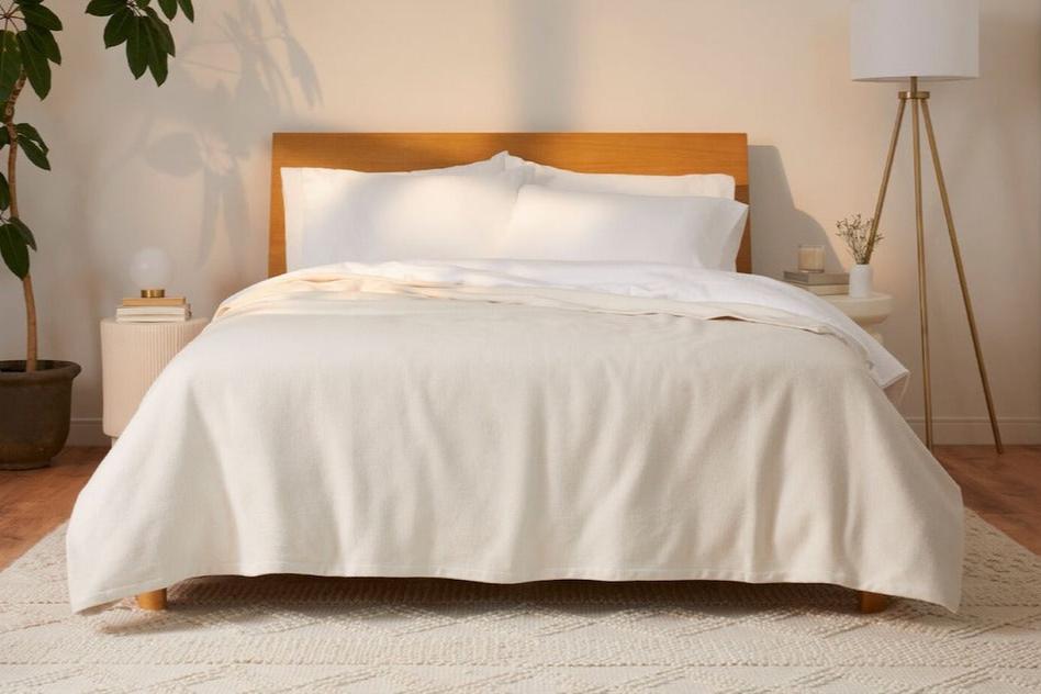 Cozy Woven Blanket, cream, on a mattress. Front view.