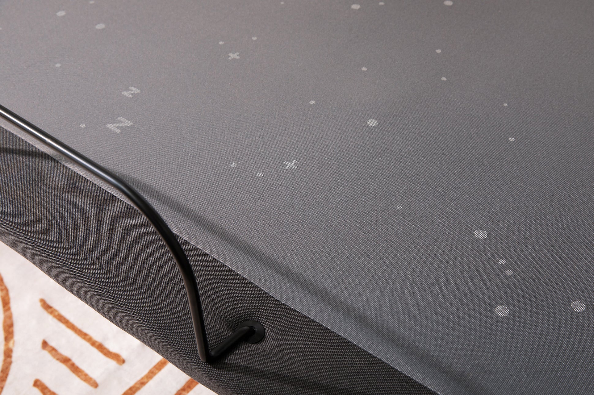 Close-up image of the bottom of the Adjustable Base. It's made of a dark fabric with a bar at the bottom to prevent the mattress from sliding off.