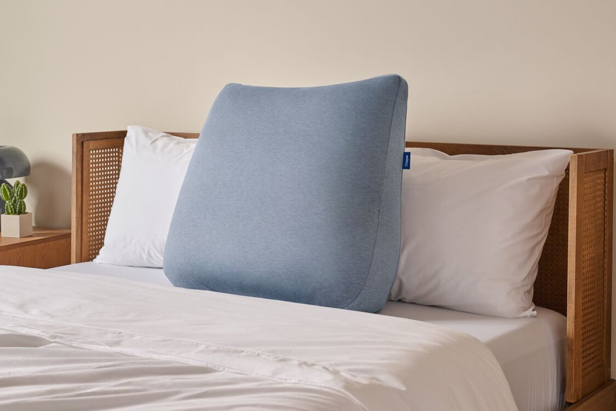 Casper's Backrest Pillow leaning against two head pillows in a bed