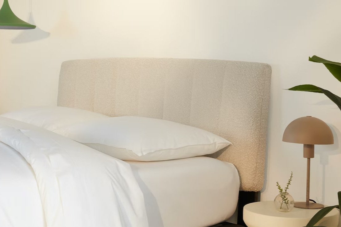 A fully made bed with a Bliss Attachable Headboard, cream color. Side view.