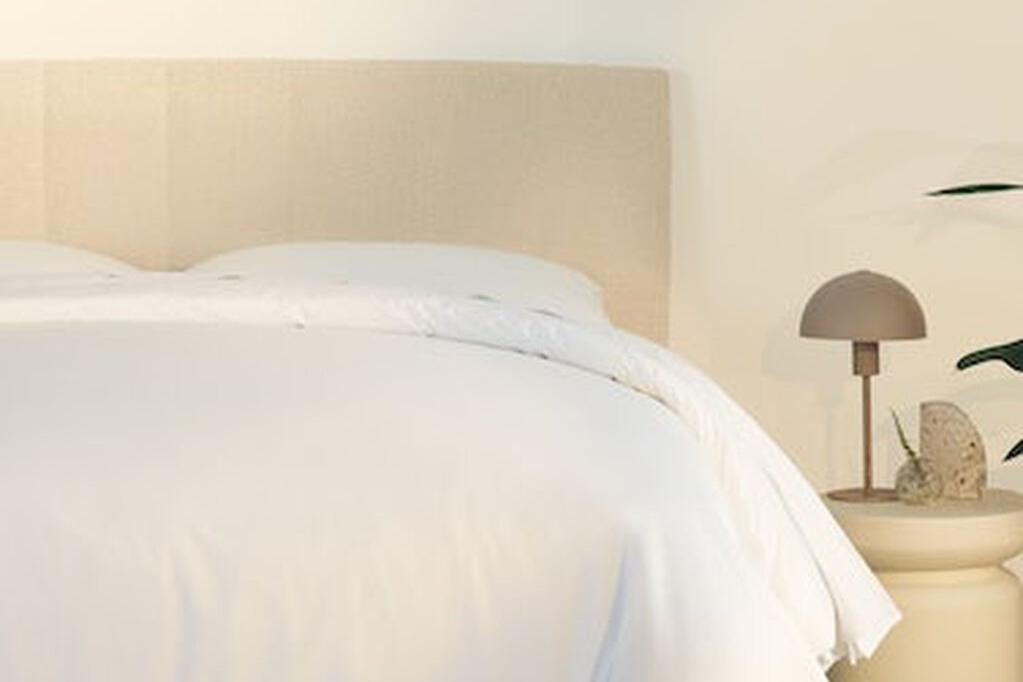 A fully made bed with a Bliss Attachable Headboard, cream color. Close-up of right half.