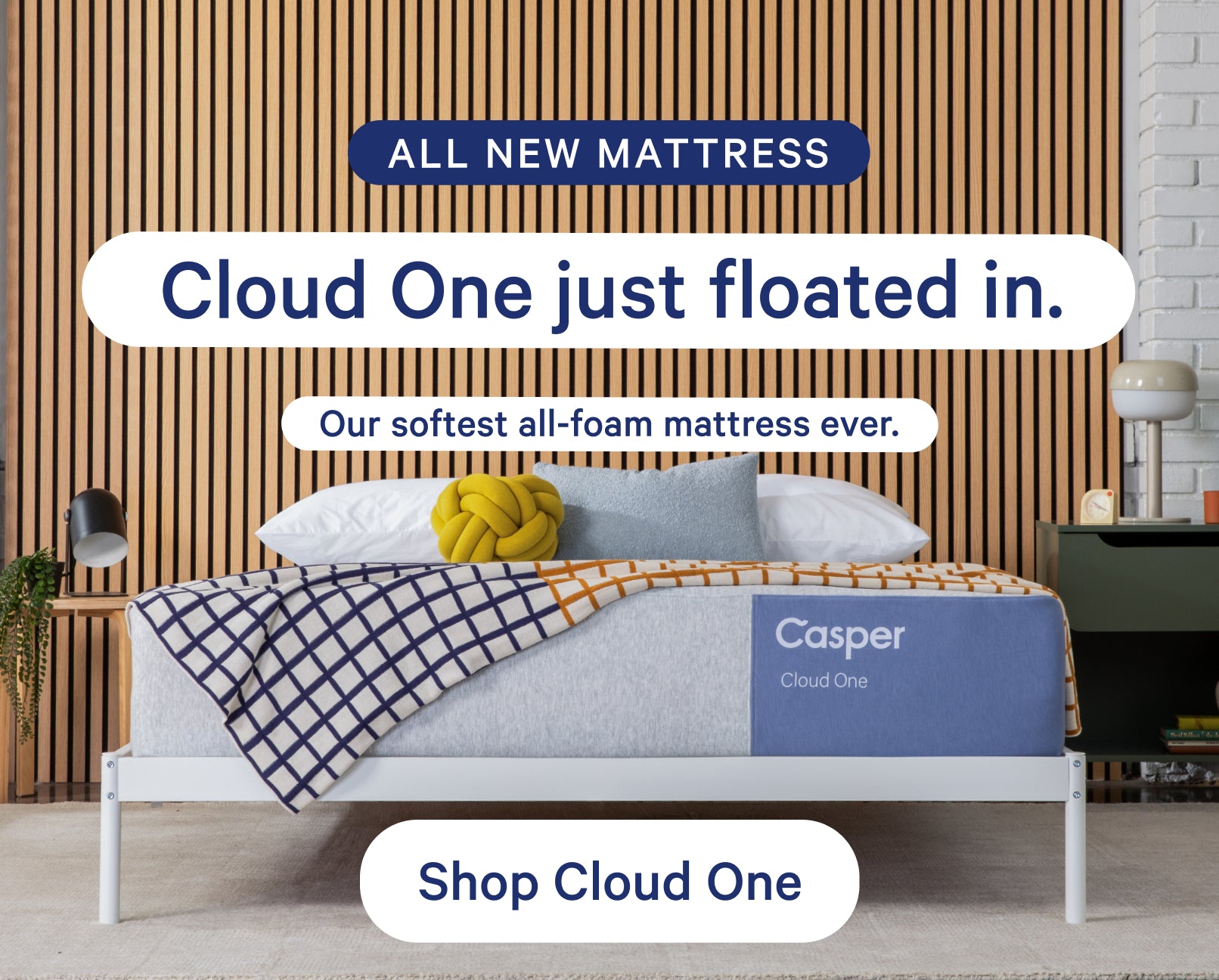 Casper's Cloud One mattress on a bed frame with a blanket and pillows on top in a bedroom setting. Text appears on the image that says, "All new mattress. Cloud One just floated in. Our softest all-foam mattress ever. Shop Cloud One."