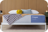 Casper's Cloud One mattress on a bed frame with pillows and a blanket folded on top