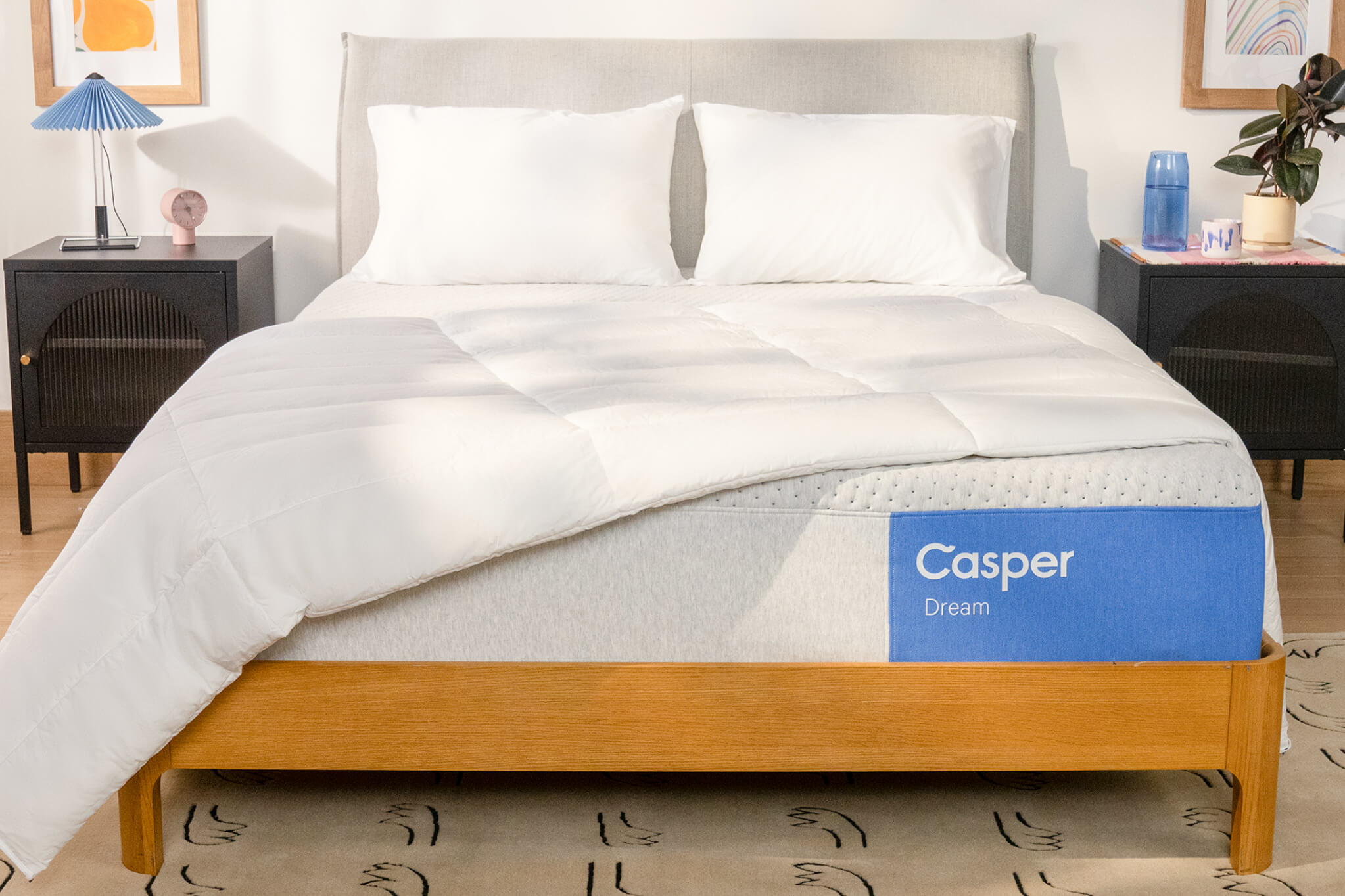 Front-facing image of the Casper Dream mattress with two pillows and a blanket folded on top.