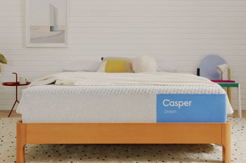 Casper's Dream mattress on a bed frame with pillows and a blanket folded on top.