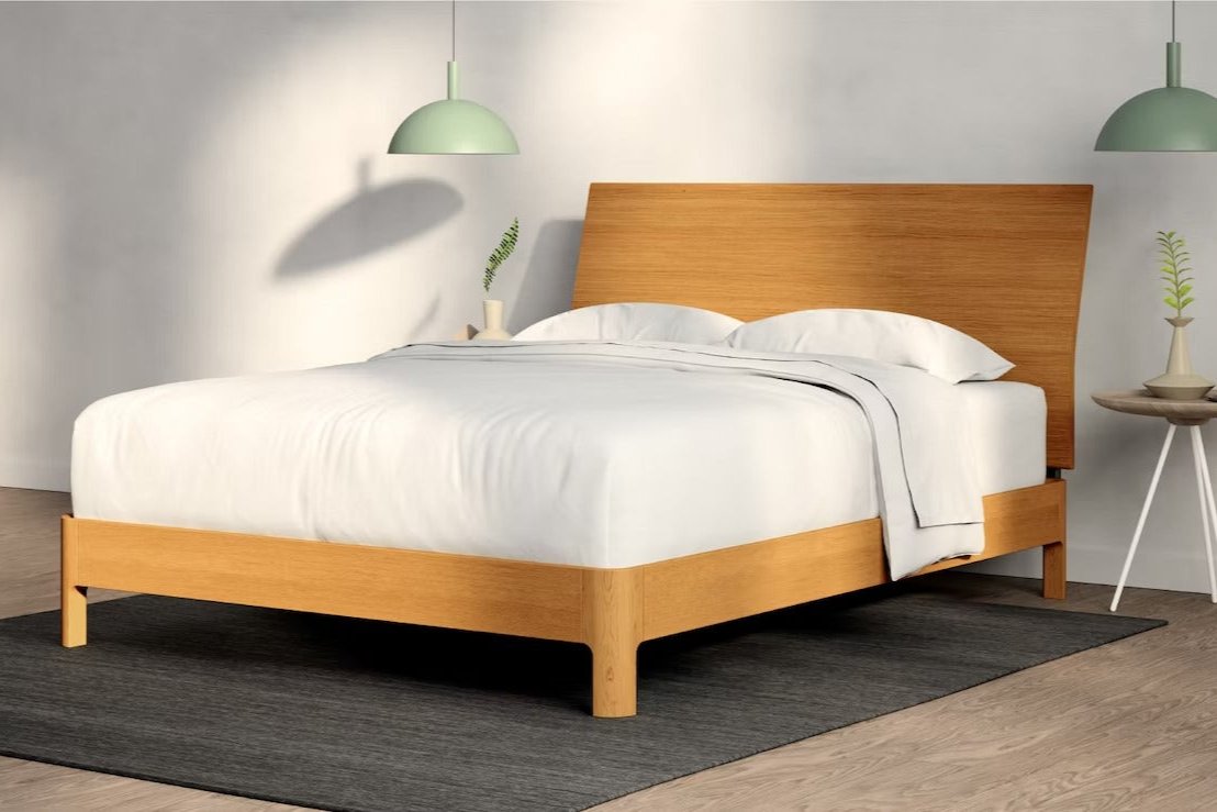 A fully made bed with a Repose Bed Frame and wooden headboard. Corner View.