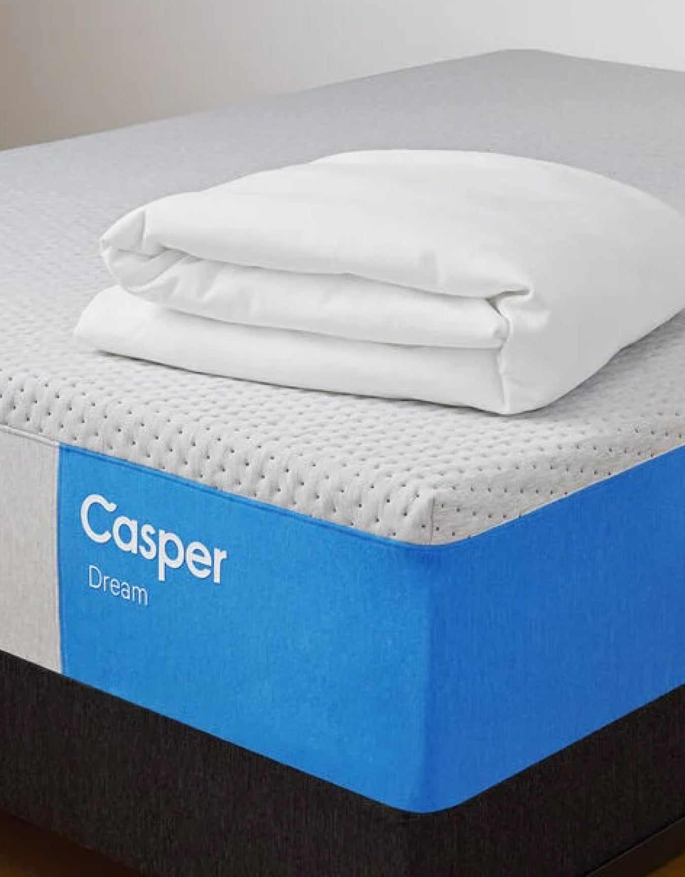 A casper Dream mattress on a foundation with a folded blanket on top.