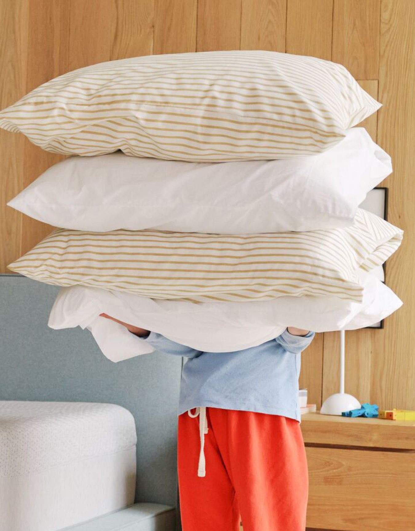 A person holding a stack of different pillows