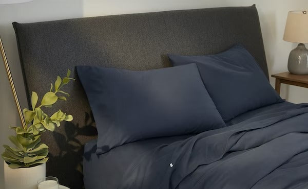A made bed with SuperSoft sheets and pillowcases, indigo colored.