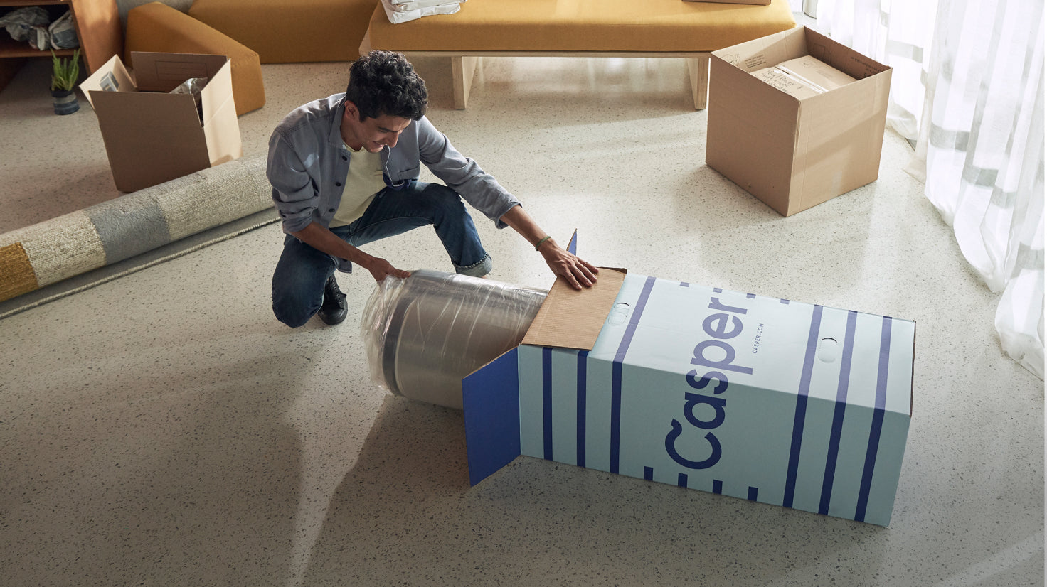 A man unboxes his new Casper mattress in a bedroom.