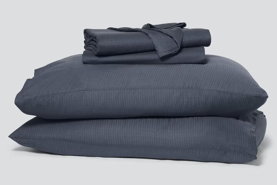 Folded pillowcases and a hyperlite sheet set, indigo, sitting atop two pillows
