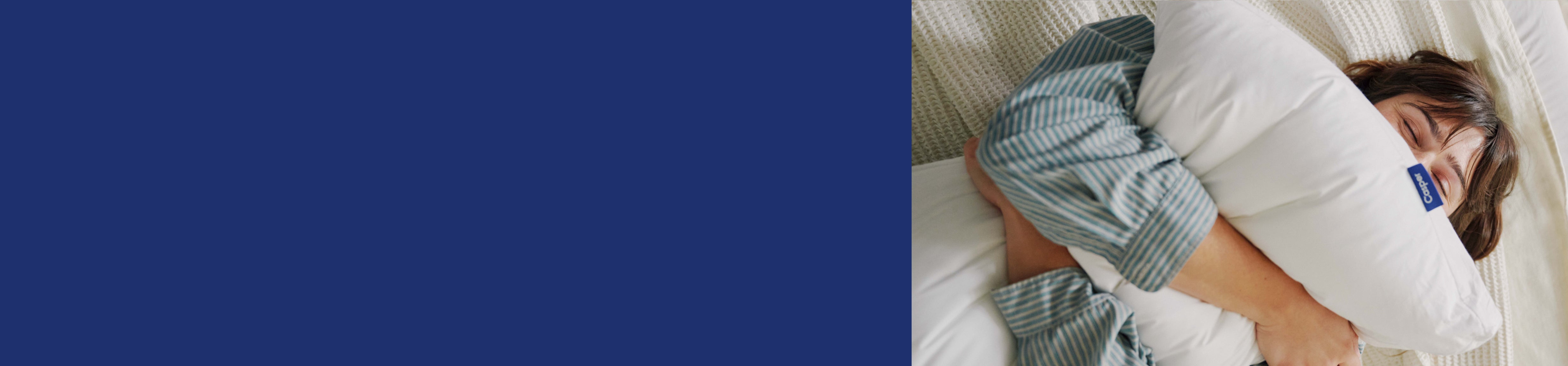 A person lying in bed squeezing a pillow