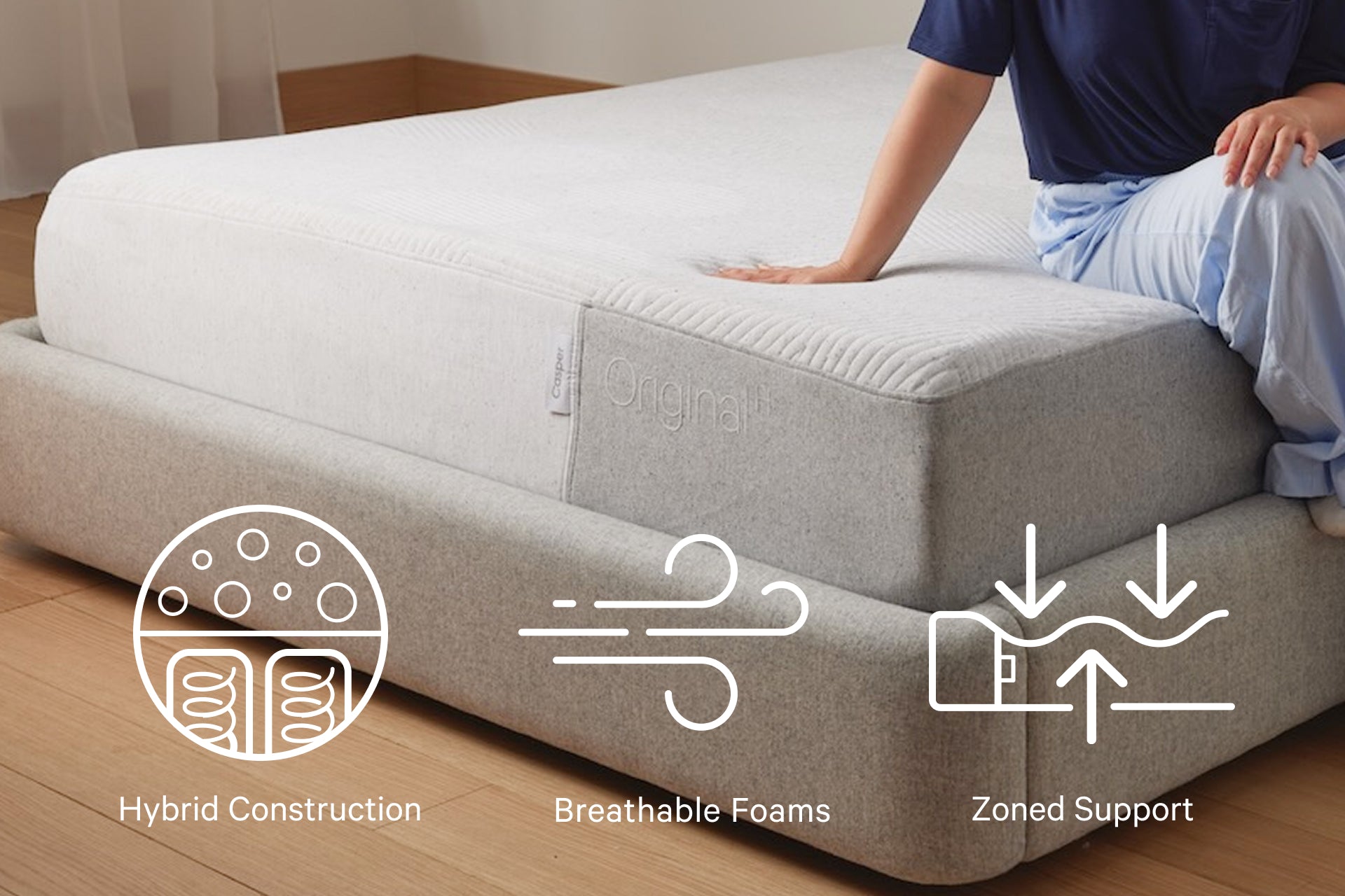 A person sits on the edge of their Original Hybrid mattress. Features include hybrid construction, breathable foams, and zoned support.