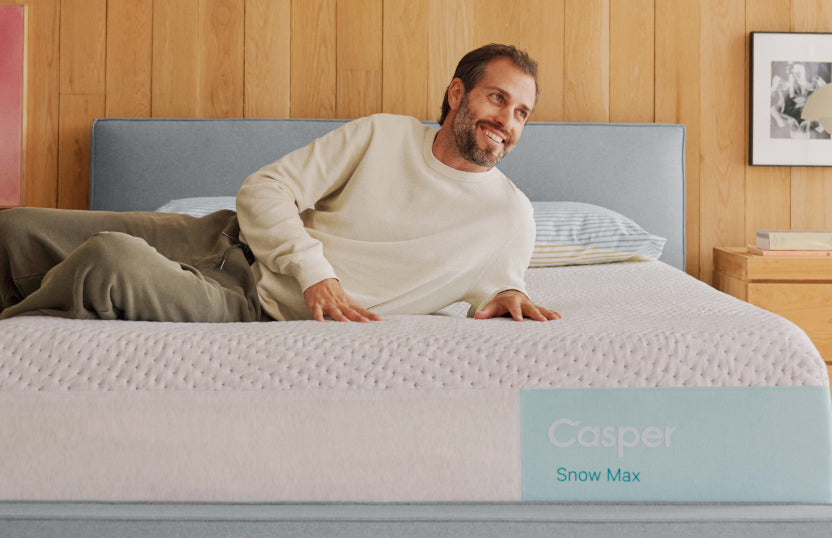 Man lying on a Casper Snow Max mattress in a bedroom setting