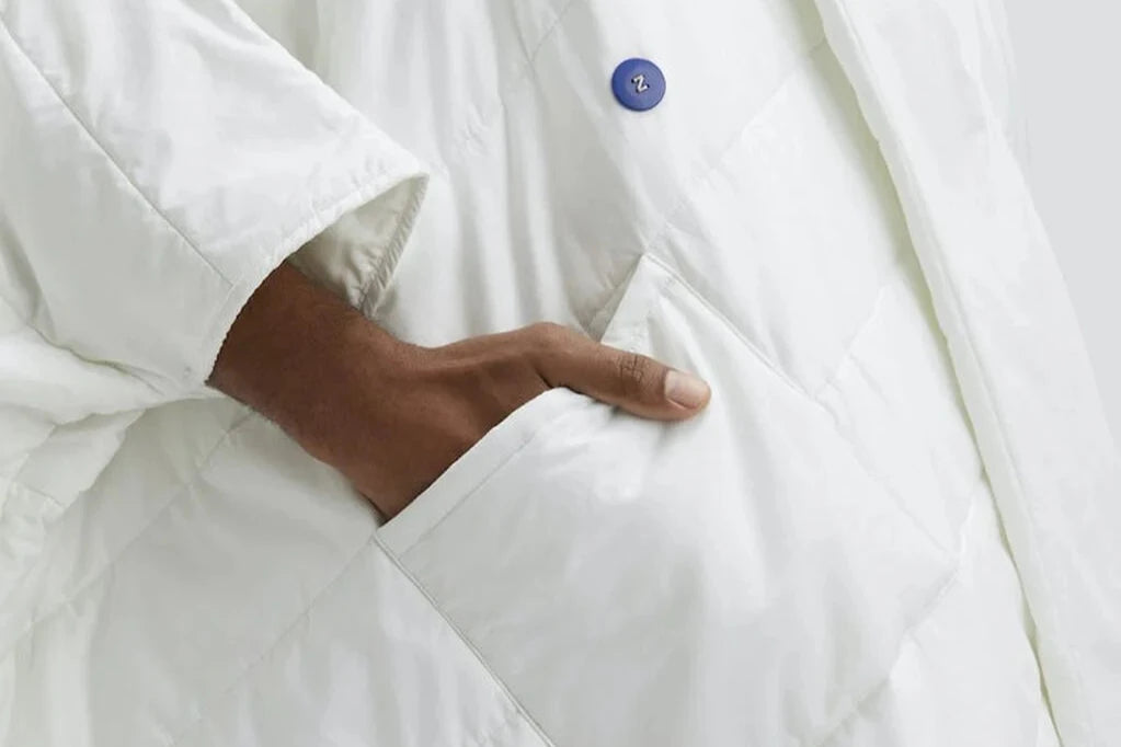 Close-up of a person's hand resting in a pocket of the Snoozewear Blanket Robe, white