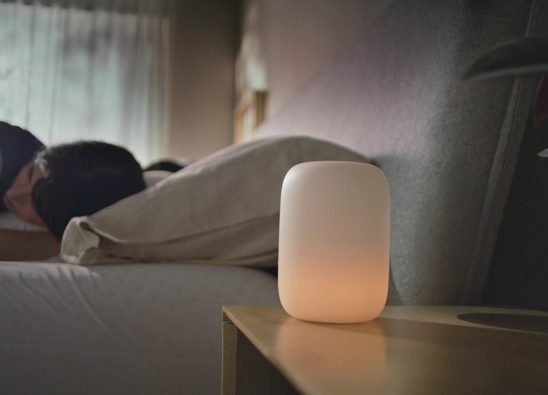 Person lying in bed with a night light on a bedside table