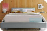 Casper's Snow Max mattress on a bed frame with pillows and a blanket folded on top.