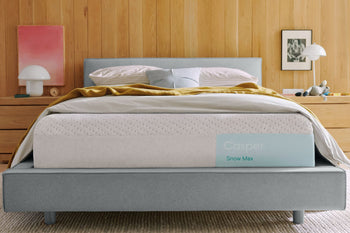 Casper's Snow Max mattress on a bed frame with pillows and a blanket folded on top.