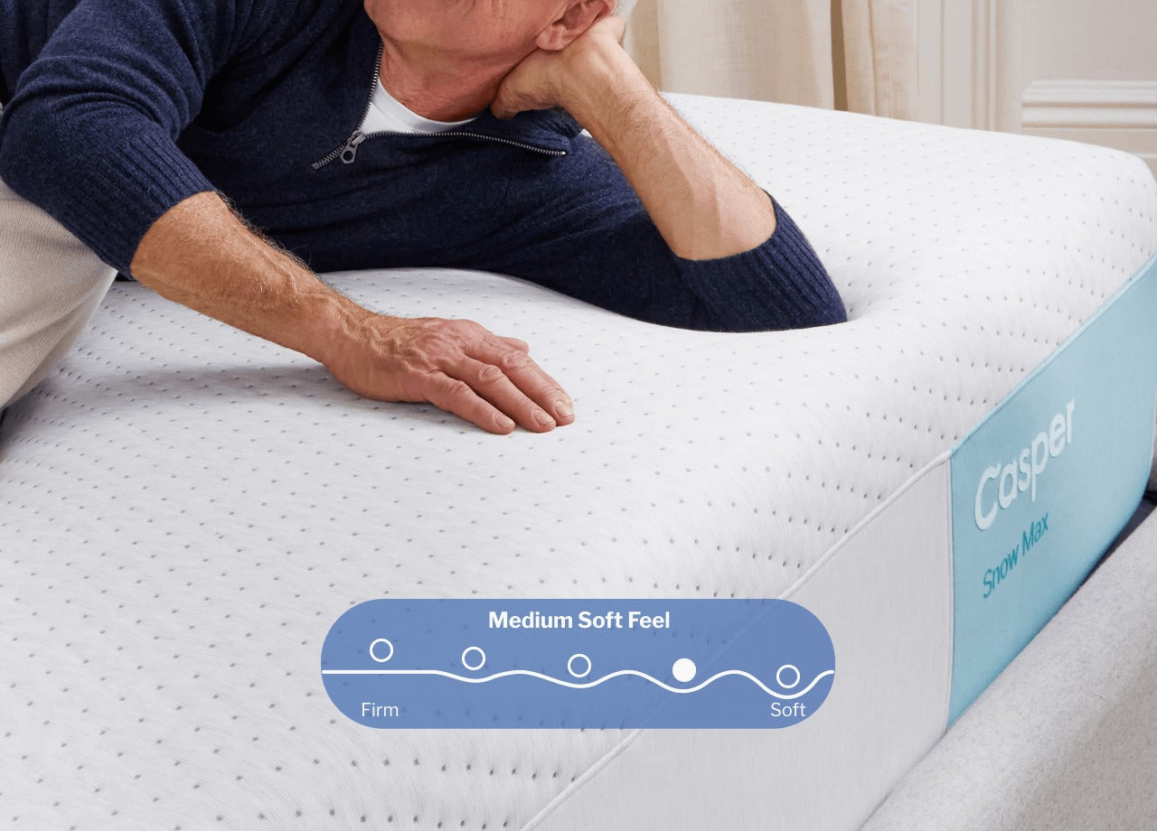 A person lies on their side near the corner of a Casper Snow Max mattress. A digital illustration placed on the image shows that this mattress has a Medium Soft feel, slightly more soft than it is firm.
