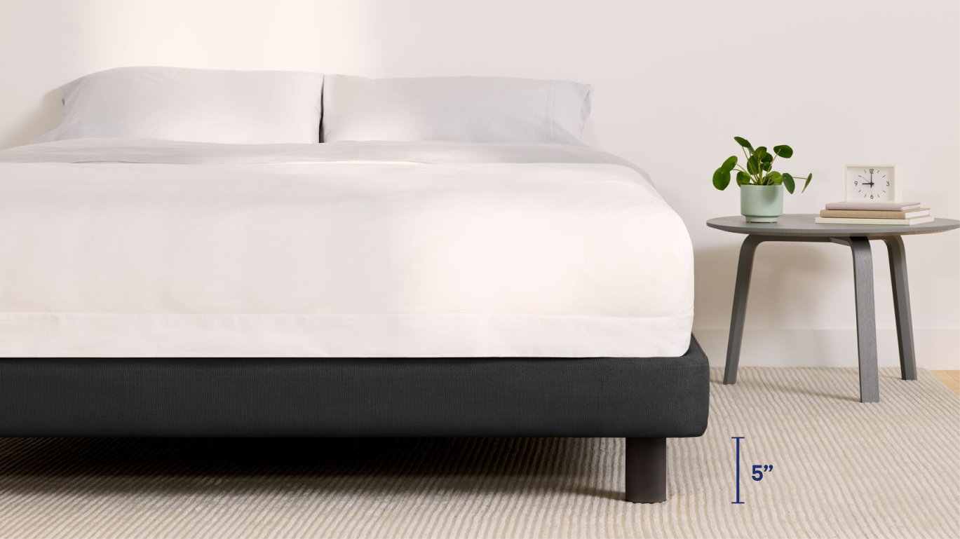 Fully dressed bed on an Upholstered Bed Frame, midnight color. A graphic at the bottom of the image indicates five inches of underbed clearance.