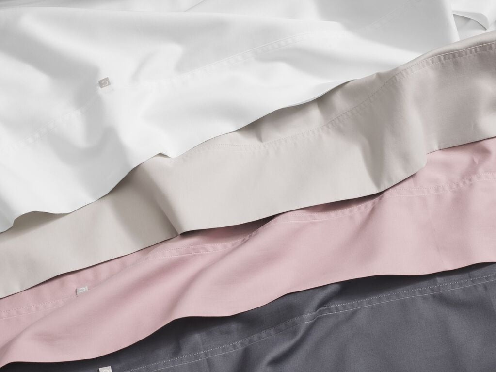 Three Sateen sheet sets, various colors, stacked on top of each other
