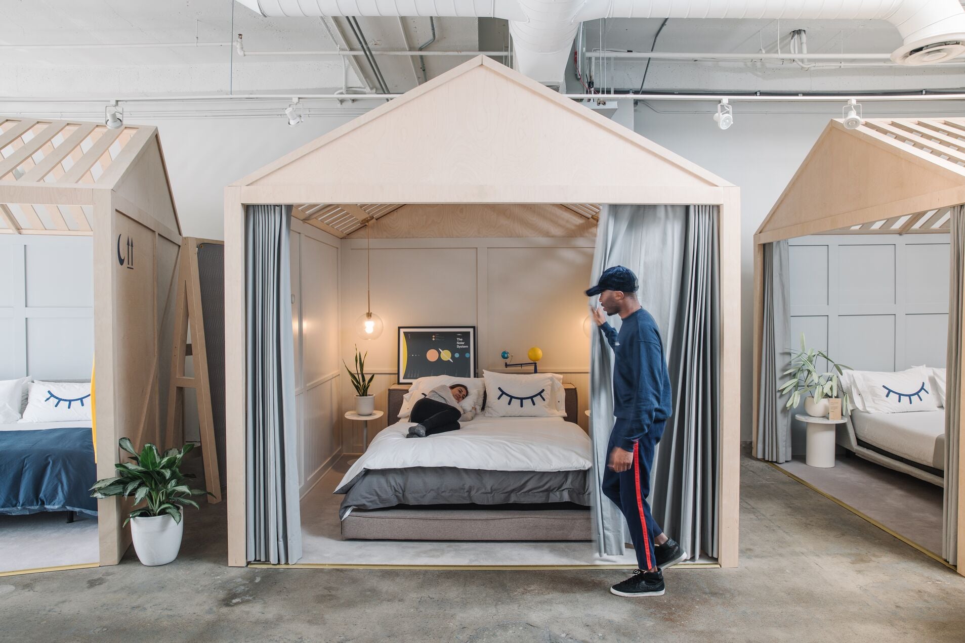 Image of a customer testing out a mattress in a Casper retail store with a store associate guiding them through the store.
