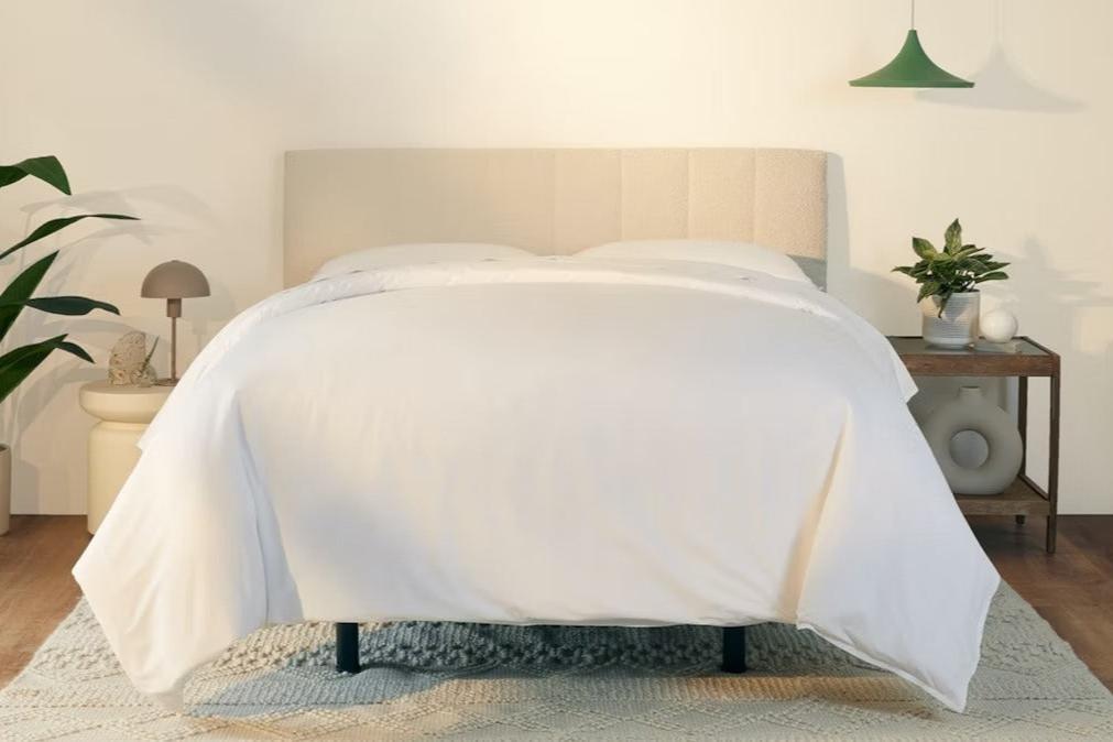 A fully made bed with a Bliss Attachable Headboard, cream color. Front view.