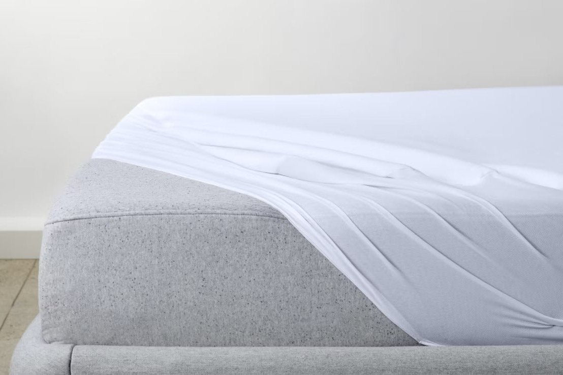 A breathable mattress protector put on a mattress with one corner loose, featuring the mattress underneath it