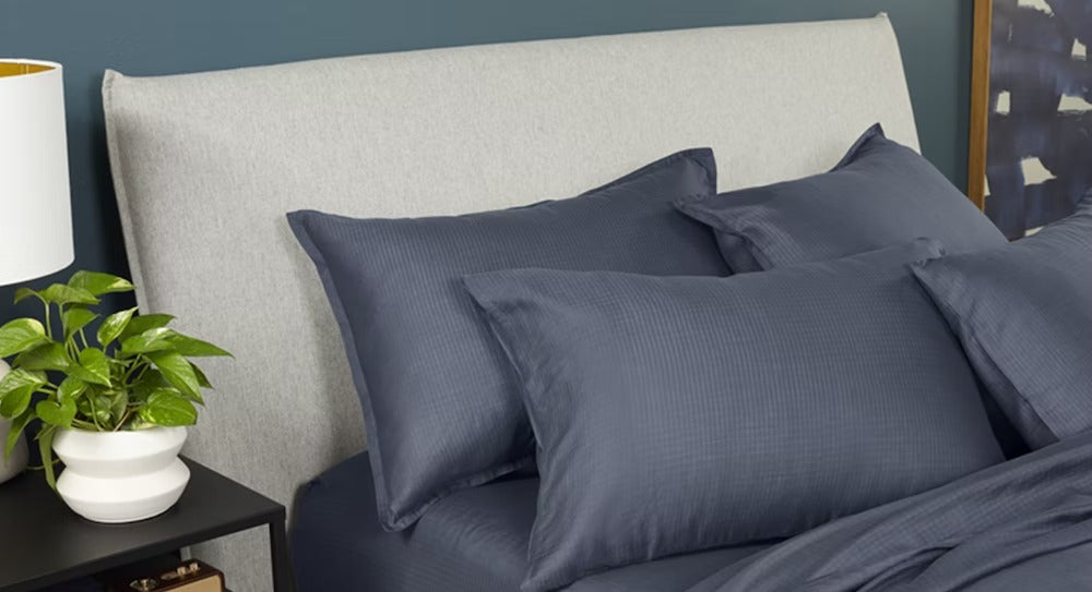 A made bed with hyperlite sheets and pillowcases, indigo colored.