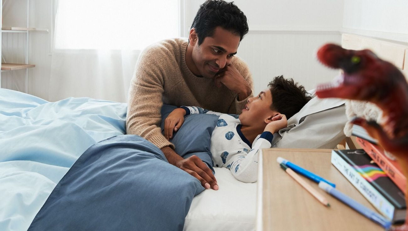 A father tucks his child into bed.