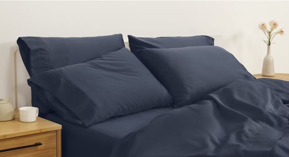 A made bed with percale sheets and pillowcases, indigo colored.