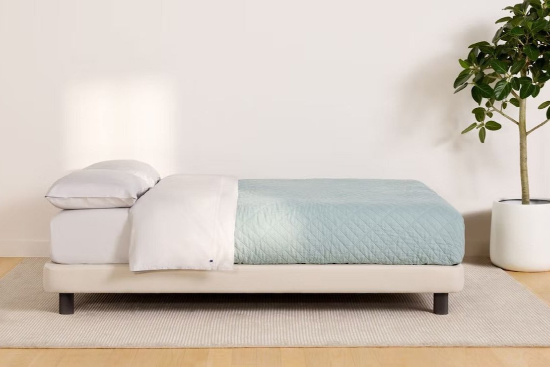 Side view of a made bed. The mattress sits atop Casper's Upholstered Bed Frame.