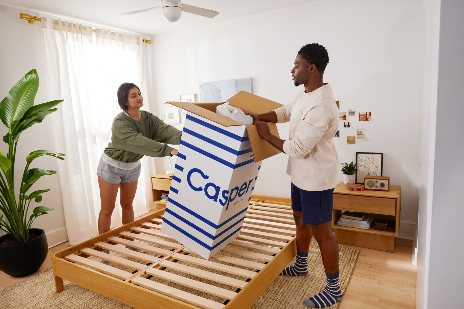 man and woman unboxing a bed in a box on a bed frame