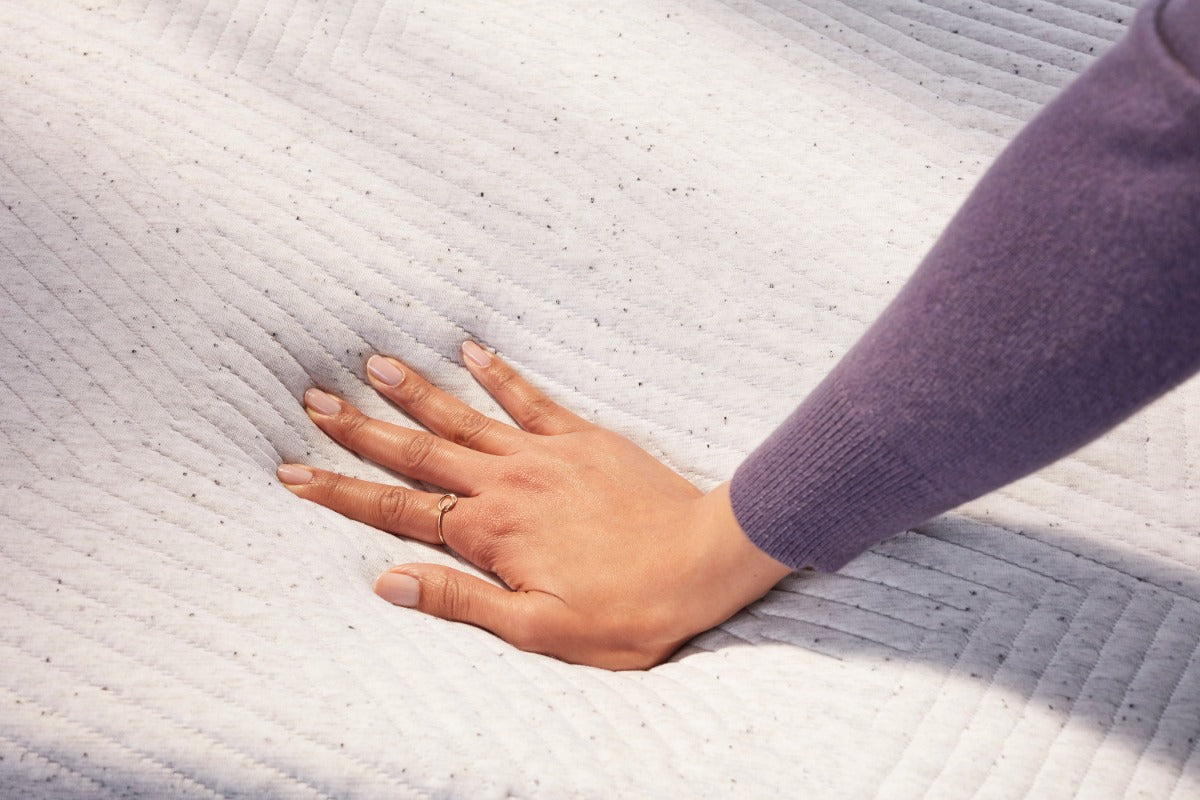 womans hand sinking into soft mattress