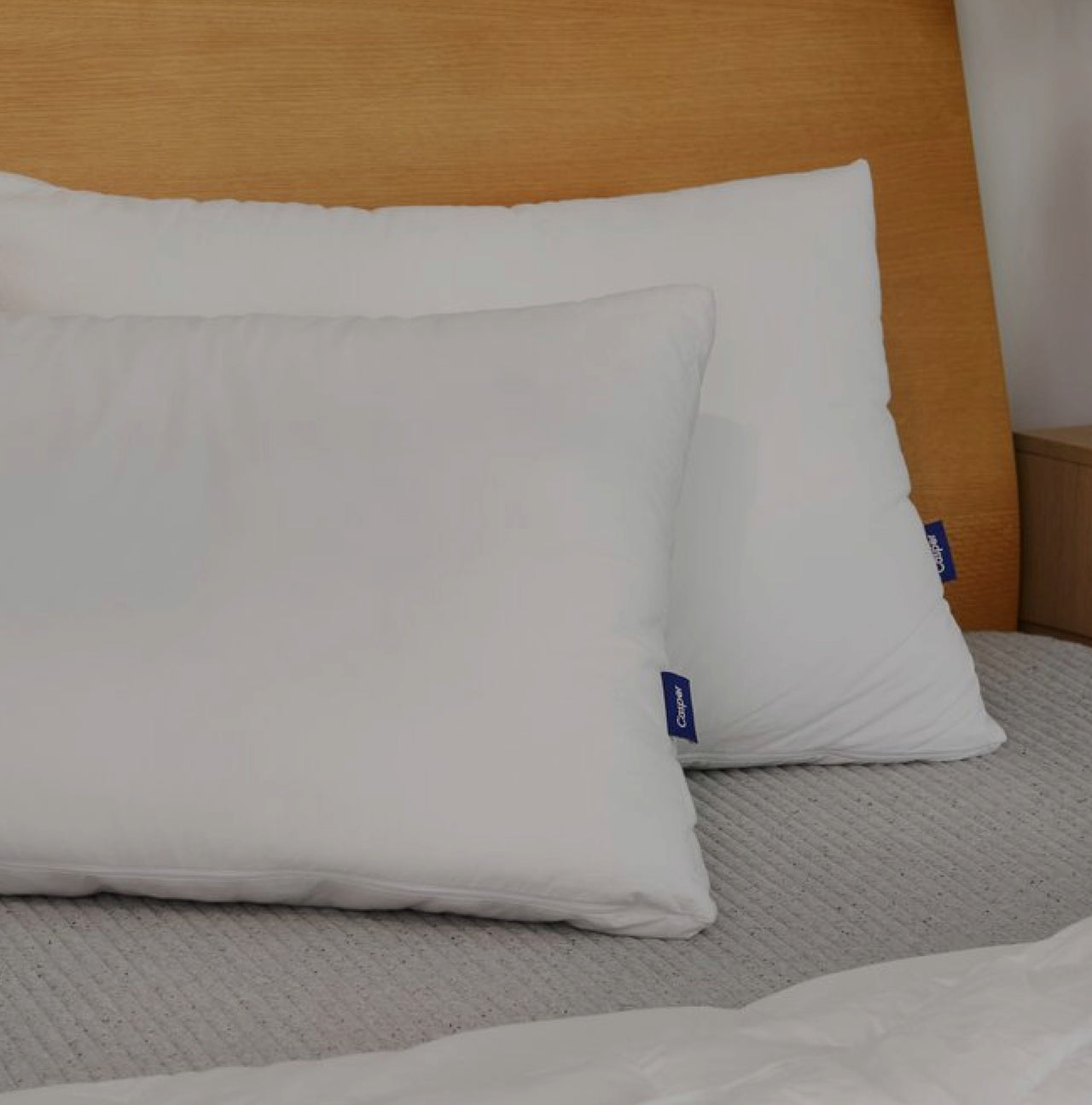 two pillows on mattress against the headboard, one in front of the other; slightly dark filter on image