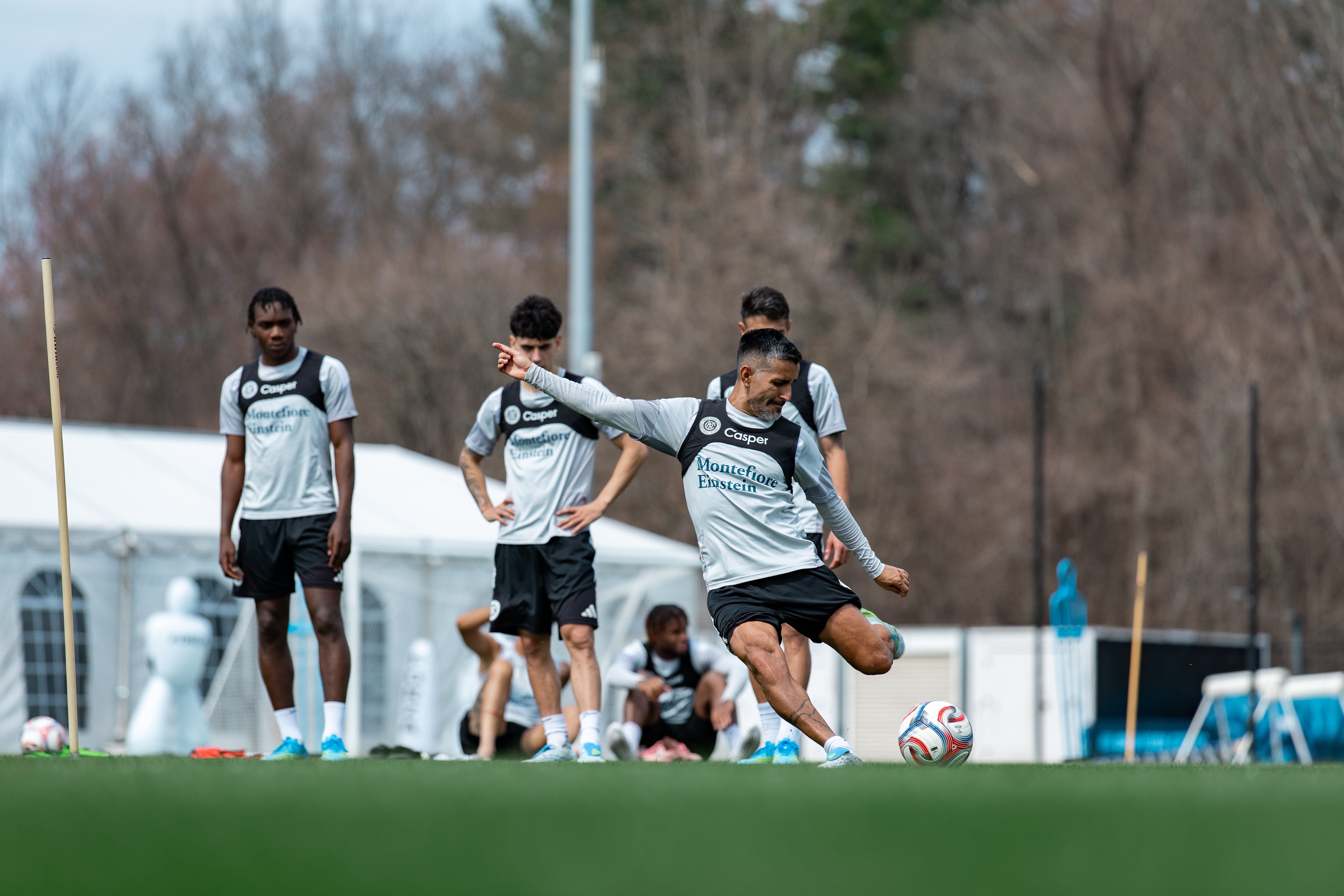 Soccer players practicing on a field with a player about to strike the ball