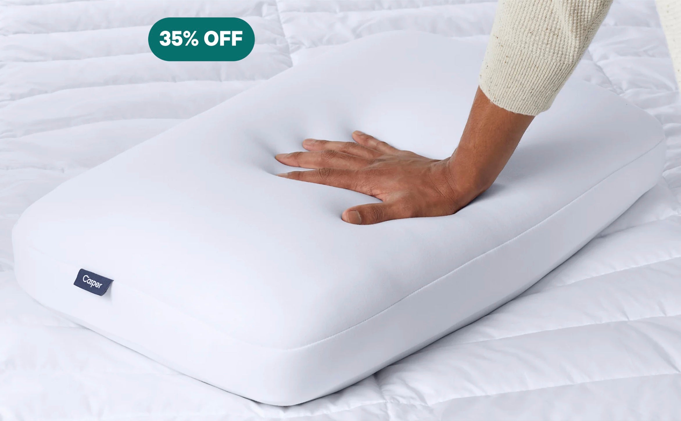 A person's hand pressing down to feel Casper's Foam Pillow.