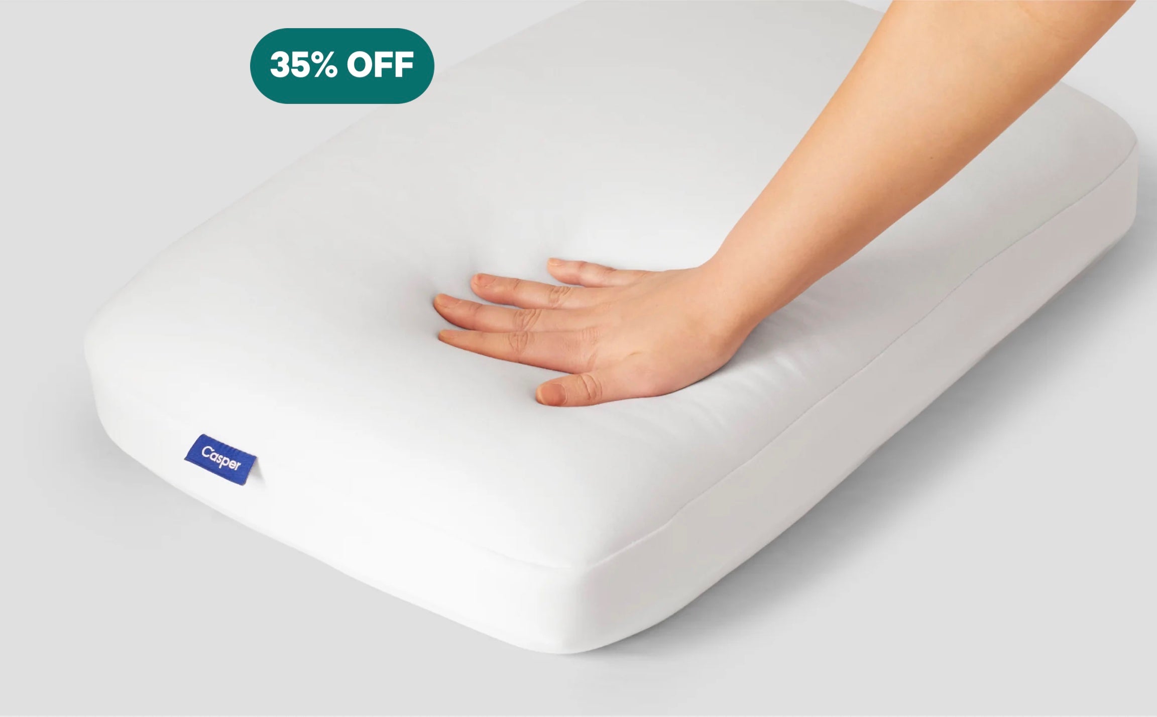 A person's hand pressing down to feel Casper's Foam Pillow with Snow Technology.