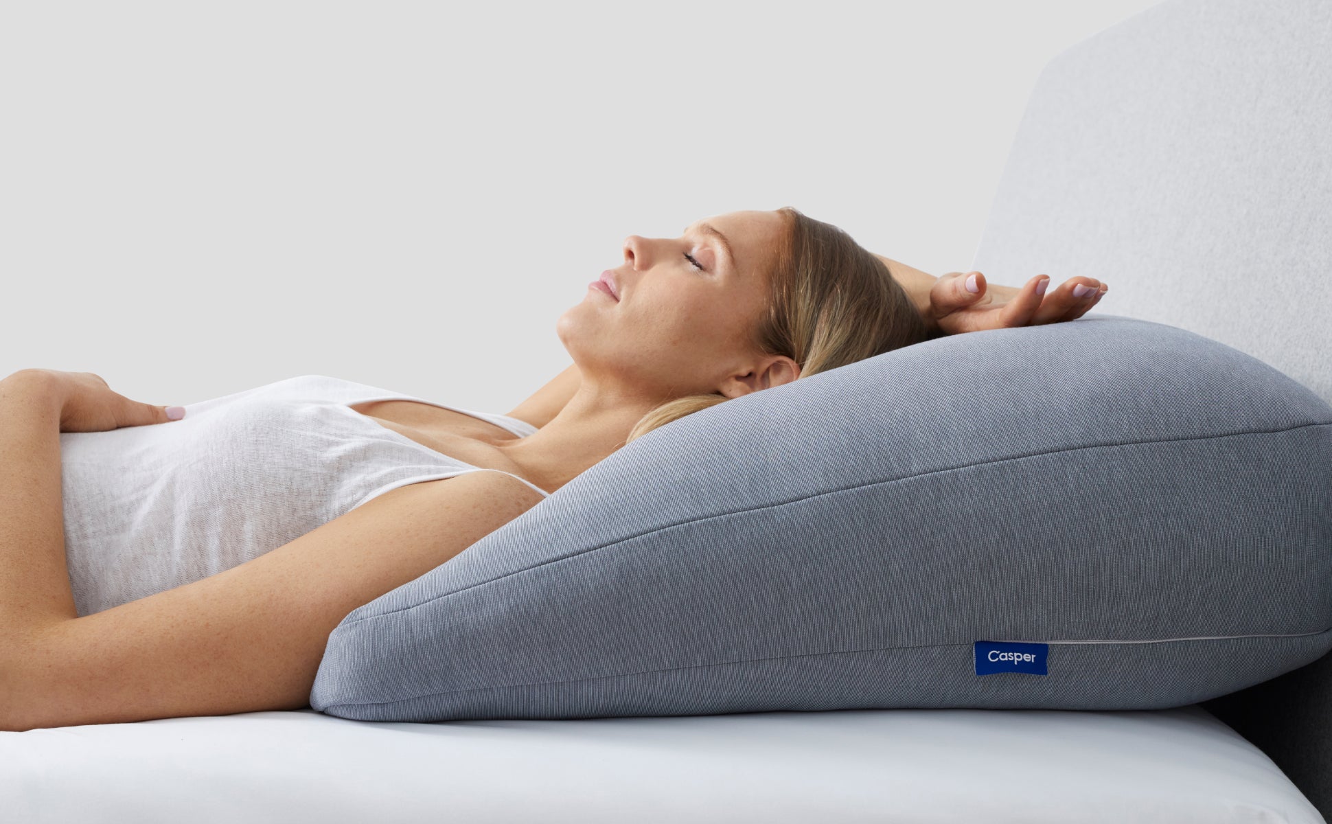 A person lying with their shoulders and head on the Casper Backrest Pillow