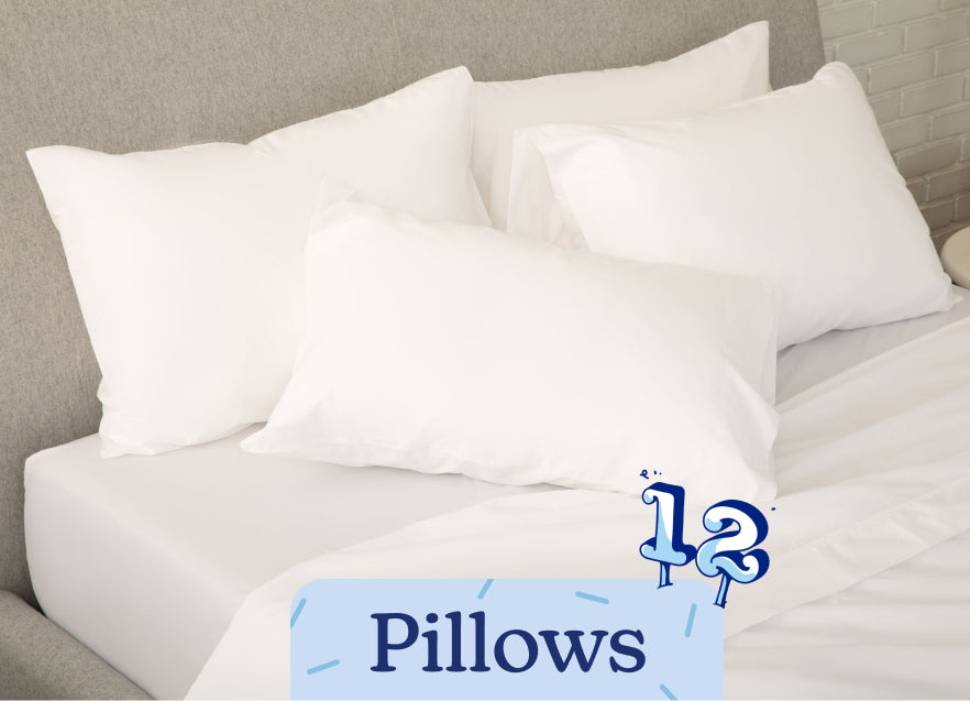 Stack of white pillows on a bed with a label indicating 'Pillows'. An illustration of the number 12 is on the image in a birthday candle style.