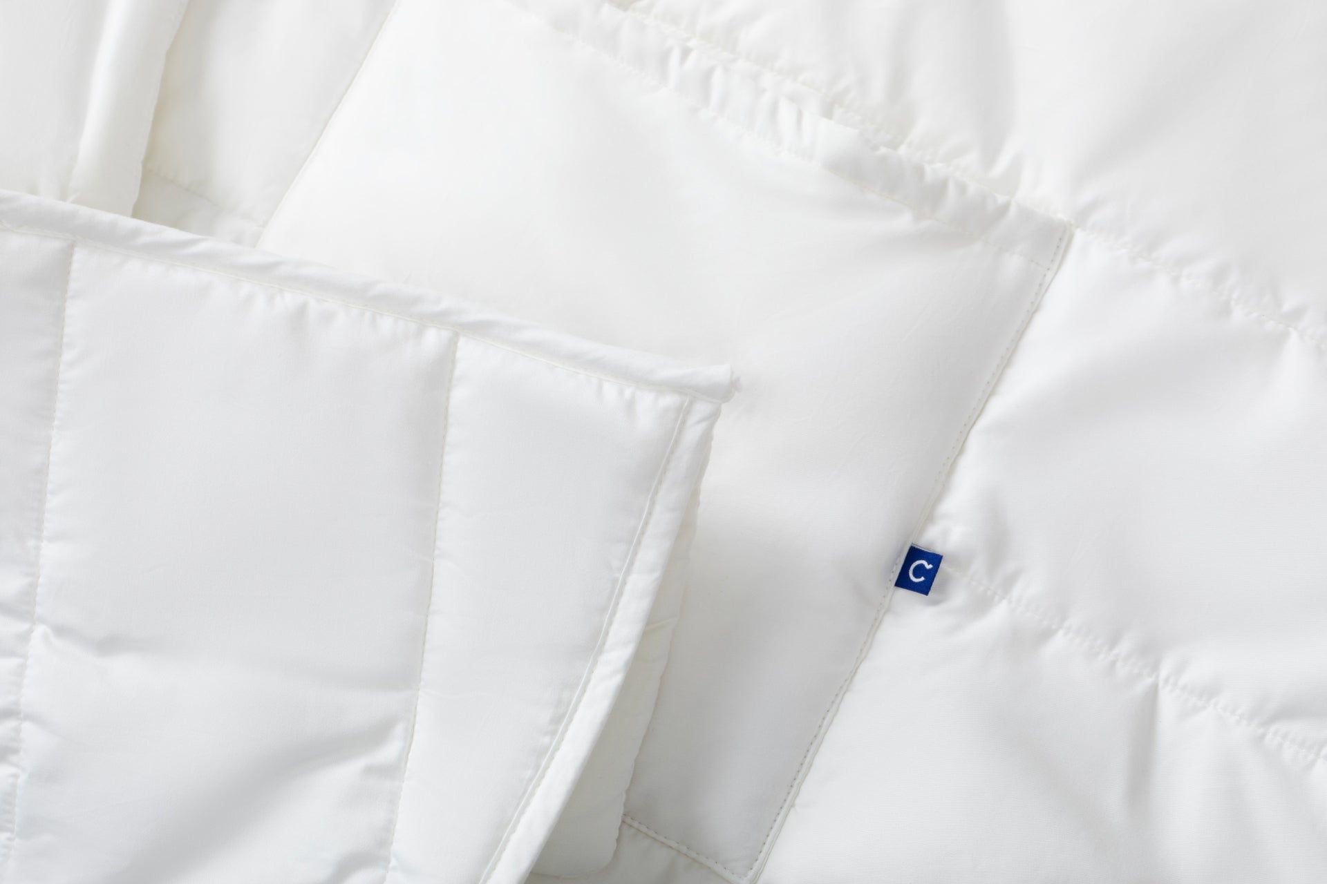Close-up of a white Blanket Robe showing the fabric texture, stitching, and a small blue, square, Casper logo tag
