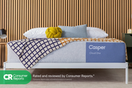 Casper's Cloud One mattress on a bed frame with pillows and a blanket folded on top. Text on the image says "Consumer Reports. Rated and reviewed by Consumer Reports. *Consumer Reports does not endorse products or services."