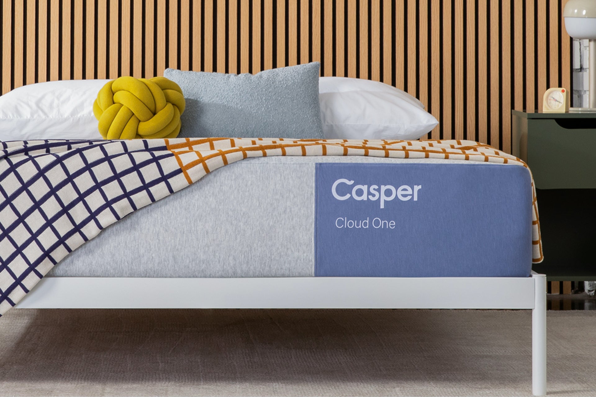 Casper's Cloud One mattress on a bed with pillows and a lamp in the background