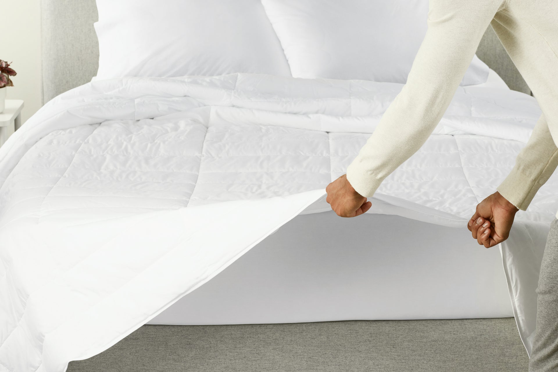 A person spreading the Down Alt Duvet over a bed