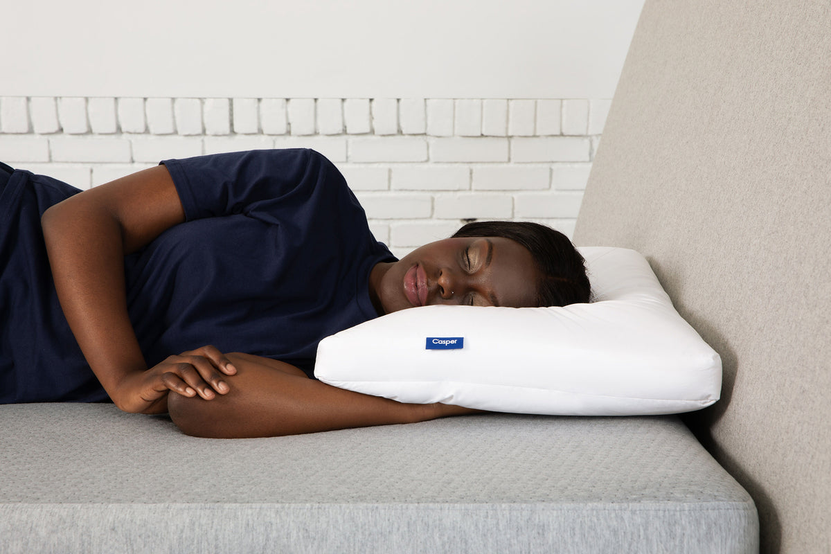 A woman sleeps on her side on Casper's Down Pillow.