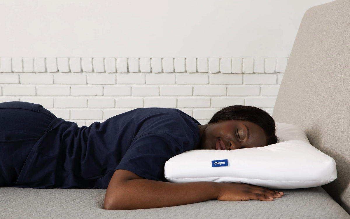 A woman sleeps on her stomach in bed.