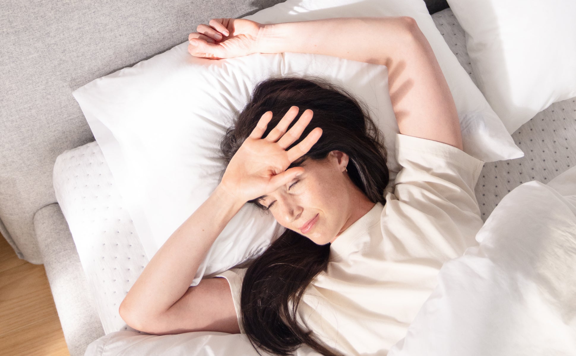 A woman waking up, lying on the Casper Down Pillow