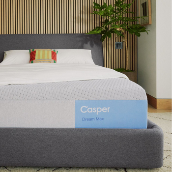 Casper's Dream Max mattress on a bed frame with pillows and a blanket folded on top.