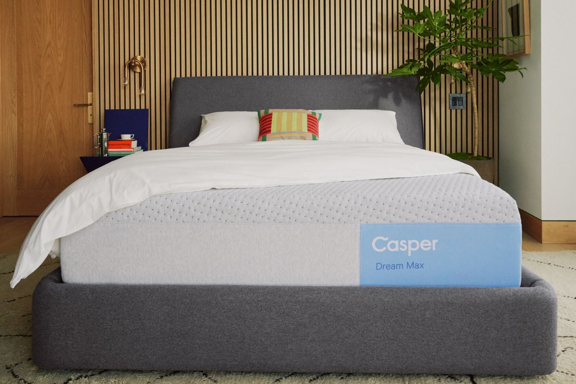 Casper's Dream Max mattress on a bed frame with pillows and a blanket folded on top.